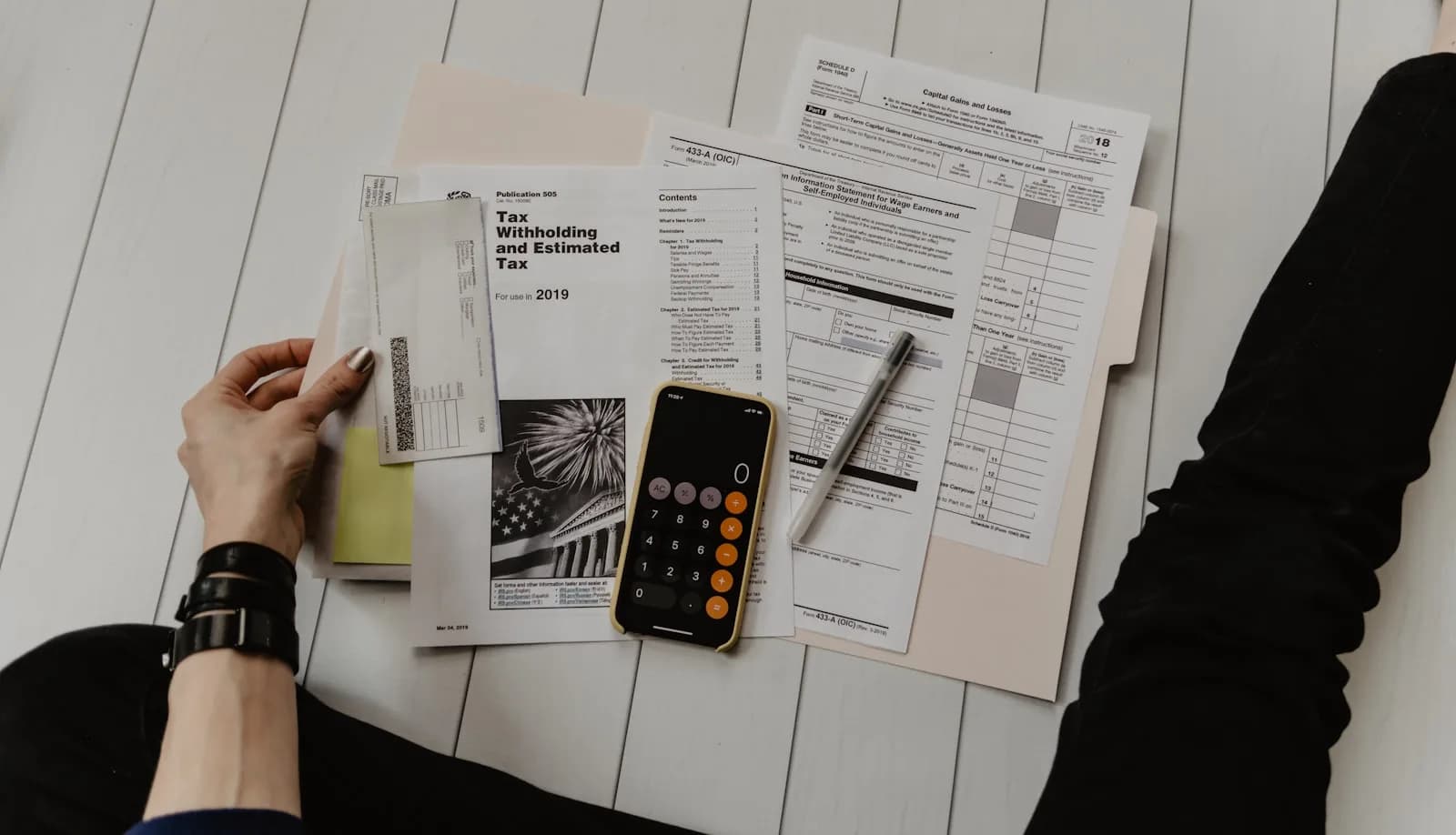 A calculator, pen and paperwork on a desk while someone works out costs